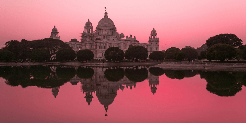 Discover the enchanting beauty of the Victoria Memorial in Kolkata, India, bathed in a pink sunset glow, showcasing rich history and architecture.