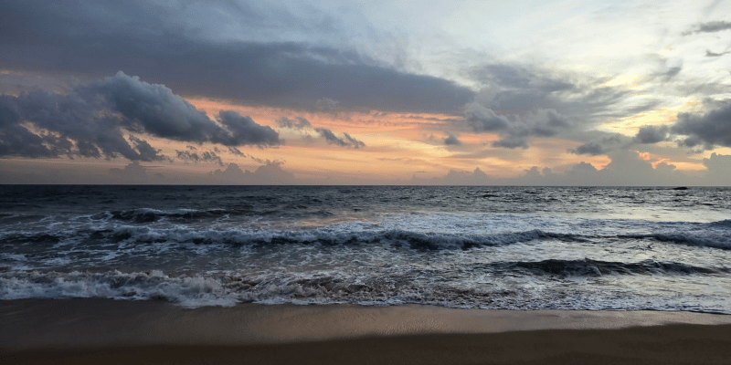 Experience the beauty of twilight on a Sri Lankan beach, where rolling waves meet the soft glow of the setting sun.